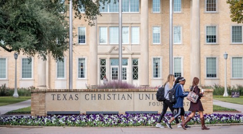 Students walking in a group by TCU sign