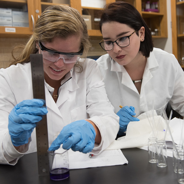 Students measuring liquid in a graduated cylinder