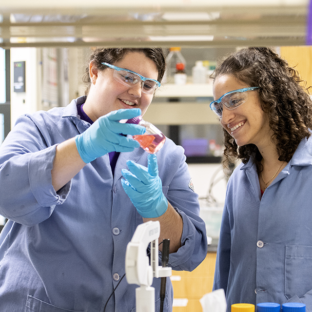 Female chemistry students discussing an experiment