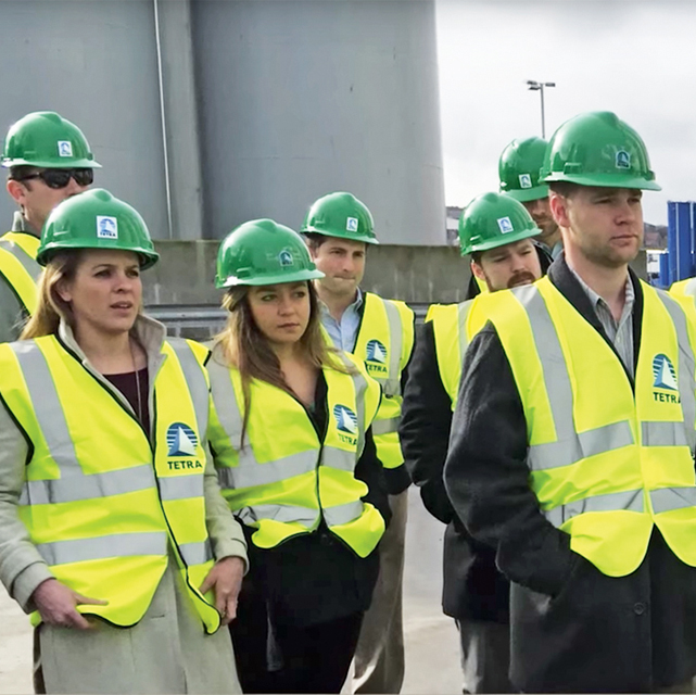 Group of Energy MBA students on site wearing hard hats and safety vests