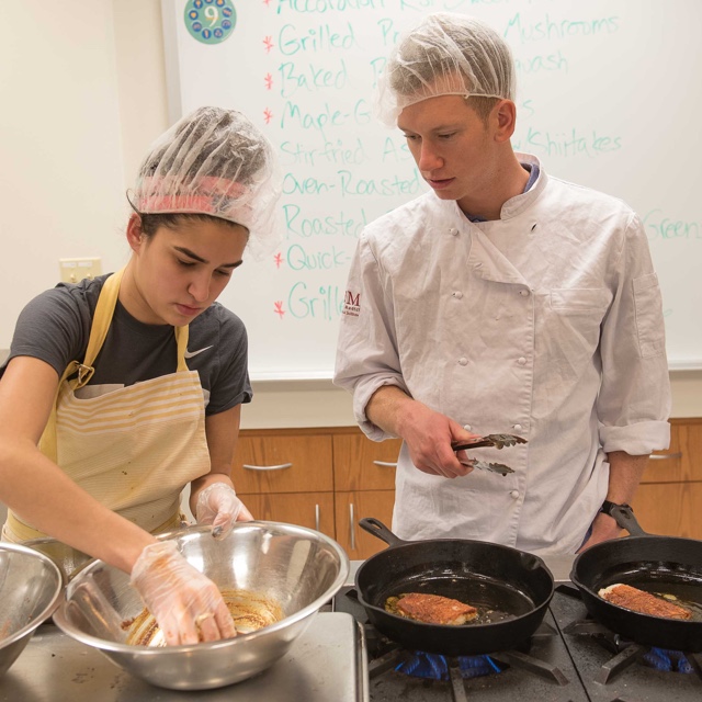 Food management students cooking fish on a cooktop