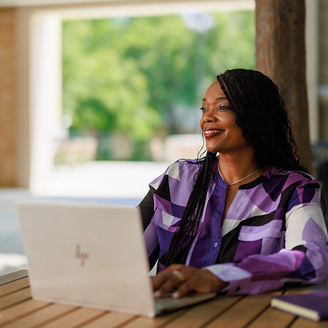 Woman works on laptop while seated at a café table